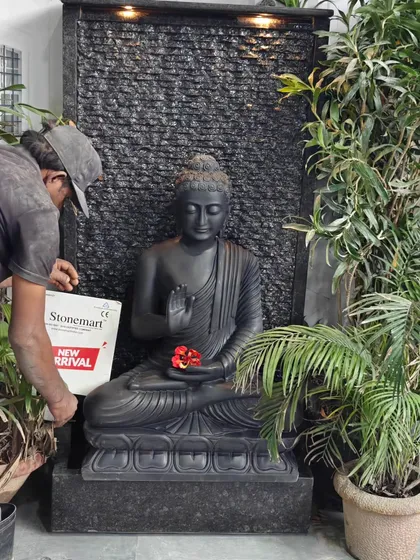 An artisan makes a final adjustment to the Buddha fountain. This piece combines a hand-carved black marble Abhaya Mudra statue with a modern ribbed granite waterfall for a unique, contemporary look.