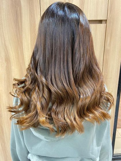 The beautiful "after" of a color correction service. We transformed the hair with a rich brown base and subtle caramel balayage, styled into soft curls to enhance the shine and dimension.