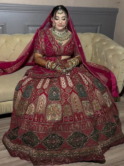 A full-length shot of the bride seated, showing the grandeur of her lehenga. The makeup is designed to be radiant and picture-perfect from head to toe.