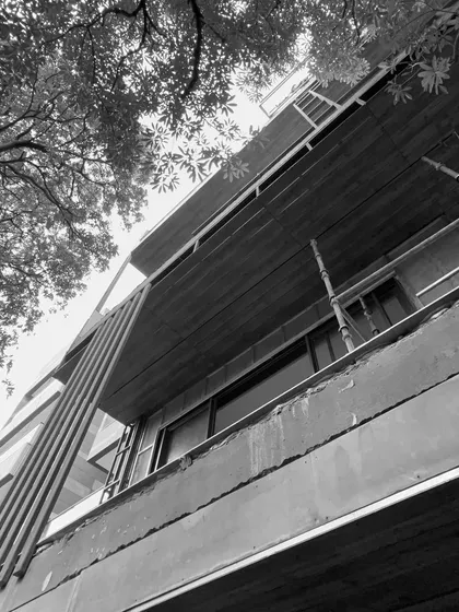 A black and white shot capturing the honest layers of architecture during construction. The textures of raw concrete, the rhythm of the structural frame, and the scaffolding reveal the beauty in the process before the final finesse.