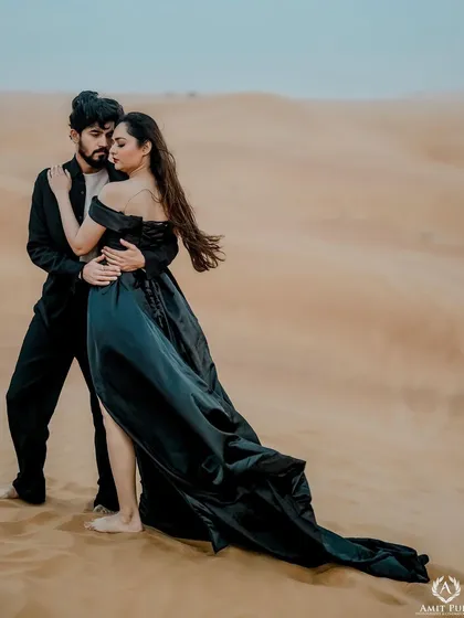 A passionate embrace in the Dubai desert. The flowing black gown mirrors the soft curves of the sand dunes, creating a dramatic and romantic photograph that feels both intimate and vast.