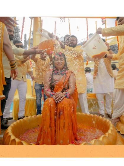 The bride, Srishti, is showered with love and turmeric by her family during her Haldi ceremony, her joyful expression captured perfectly.