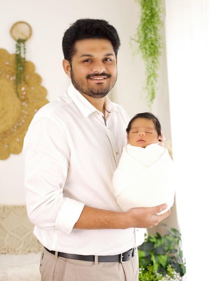 A proud father holds his sleeping newborn, a simple and powerful portrait of fatherhood.