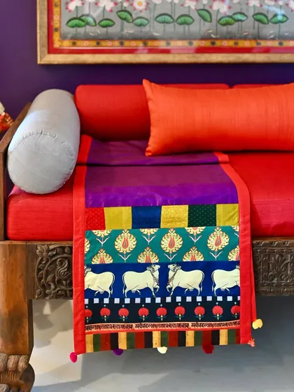 A one-of-a-kind reversible silk runner, custom-made with a patchwork of vibrant fabrics including a Pichwai-inspired cow print.