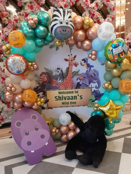 A welcome wreath for a jungle party, decorated with animal-themed balloons and props like a hippo and gorilla.