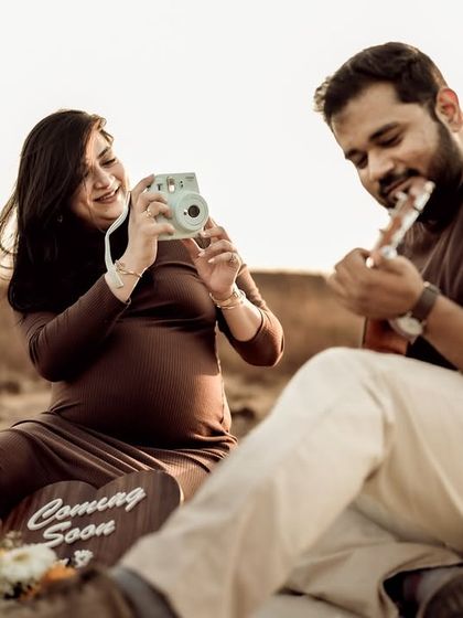 A fun and candid moment during a picnic-themed shoot. She takes a photo of him playing the ukulele, capturing the playful dynamic of their relationship.