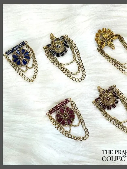 Our collection of antique-style chained brooches adds a touch of vintage elegance to coats and jackets. Available in multiple colors like royal blue, deep red, and classic black, these pieces connect with delicate gold-tone chains.