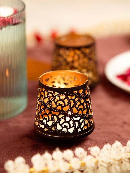 A beautiful shot of a decorative candle holder, lit from within. The warm glow and festive background make this perfect for a Diwali or holiday campaign.