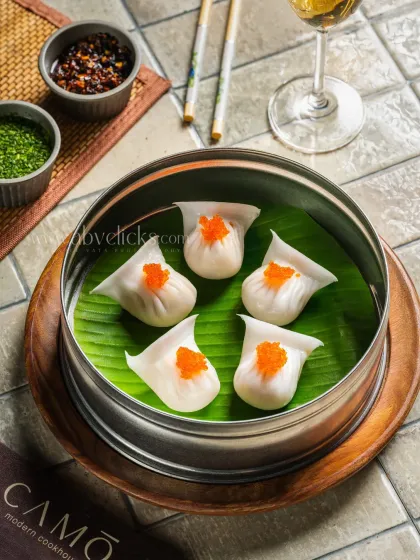 Elegant dim sum topped with roe, served in a steamer for Camo, Noida. The top-down view is perfect for menu design.