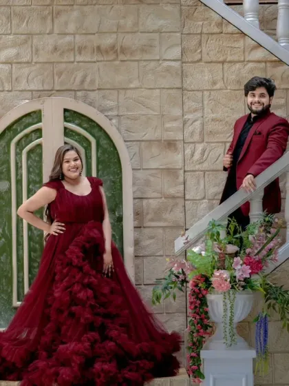 Here is another example of a coordinated couple's outfit. The groom's deep red suit complements the bride's ruffled maroon gown, showing how you can achieve a cohesive look even with different styles of western wear.