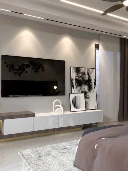 This bedroom showcases a custom floating TV unit with a combination of wood-textured and white laminate finishes. The design keeps the space feeling open and uncluttered, a key element of minimalist interior design.