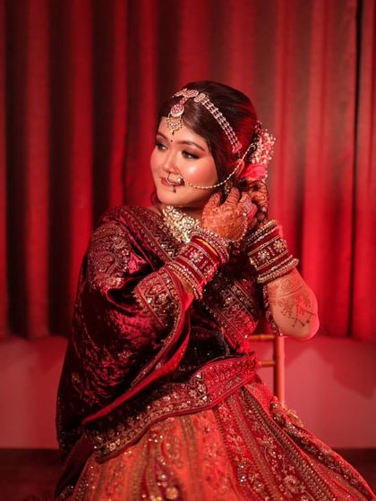A moment of quiet anticipation. This bride is getting her final touches, with her elaborate jewelry and detailed makeup ready for her North Indian wedding ceremony.
