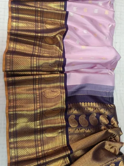 A soft pink pure Gadwal silk handloom saree with a deep blue and gold woven border.
