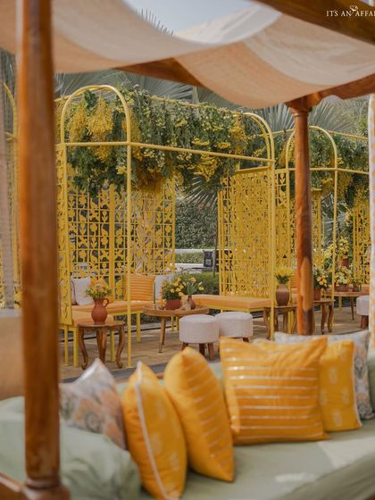 A closer look at the seating cabana, where yellow jali screens and hanging florals create a beautiful, light-filled space.