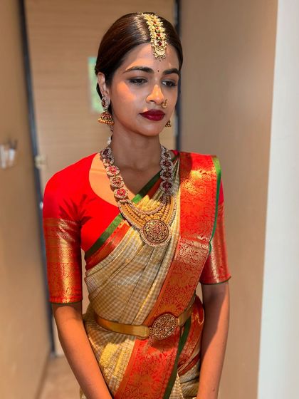 A portrait of a beautiful bride, her hair pulled back neatly to showcase her radiant face and traditional jewellery, leading into a classic braid.