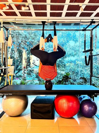 Achieving fitness is an art form. This inverted pose on the Cadillac, supported by various props, is a harmonious blend of dedication and discipline.