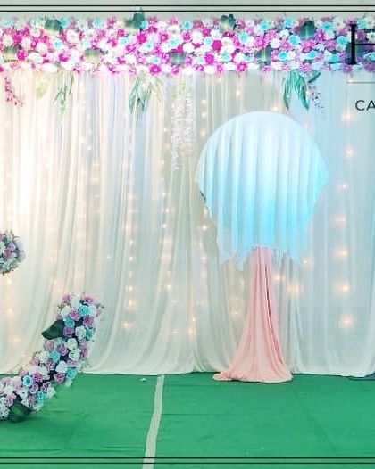 This naming ceremony stage features a crescent moon cradle decorated with purple, blue, and white flowers. The backdrop of fairy lights adds a dreamy sparkle to the celebration.