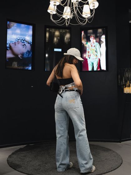 Styling wide-leg light-wash jeans with a cap and a unique top at a GAS Jeans event.