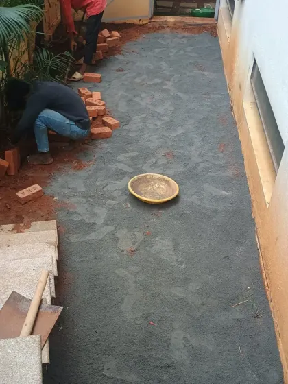 In this narrow space, we are preparing the base layer of crushed stone before laying the artificial grass. The brick border helps to frame the area.