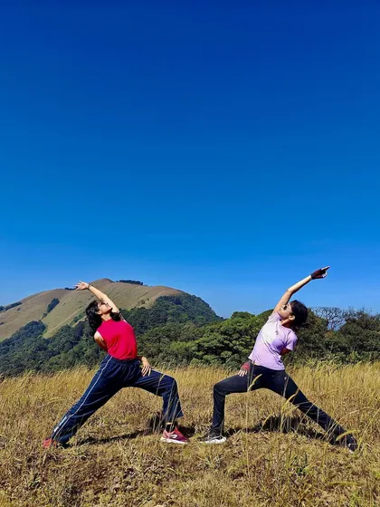 Yoga is better with friends. Here we are stretching in a partner pose after a beautiful trek in Coorg. My retreats often include activities like hiking, bringing a sense of play and community to our practice.