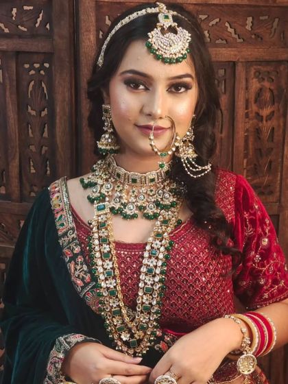 A bride wearing a layered emerald green jewellery set with a matching velvet lehenga. This monochromatic look is both regal and on-trend.