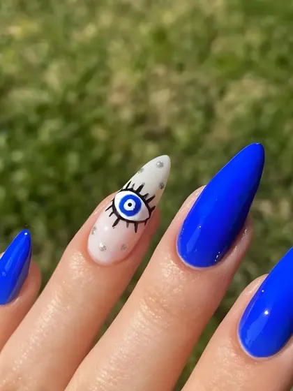 A close-up of the detailed evil eye nail art, featuring precise line work and tiny silver dot accents on a white base.