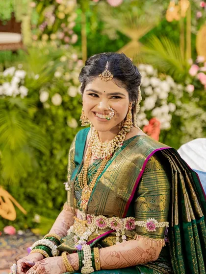 A close-up of the mom-to-be, radiant in her green saree and our custom floral jewellery. The set includes a floral kamarbandh and bajuband with pink and white flowers.