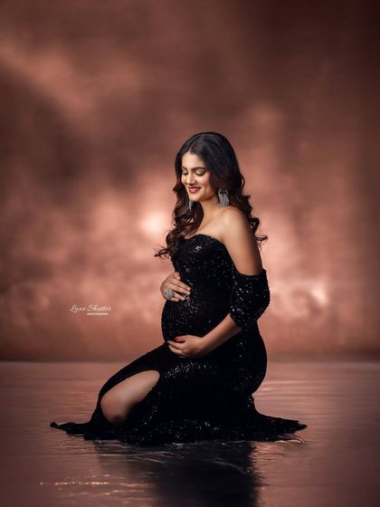 A kneeling pose that shows off the beautiful fit of the black sequin gown, with the mom-to-be cradling her bump.
