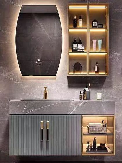 A luxurious bathroom vanity design featuring a grey marble countertop and gold accents. The backlit mirror and integrated shelving with lighting add a touch of glamour and sophistication.