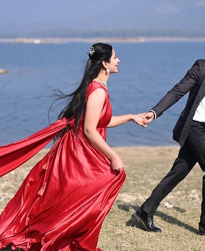A romantic walk along the lakeside. The red trail follows the bride, creating a beautiful line of color that contrasts with the natural landscape.