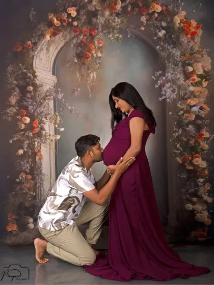 A classic bump kiss pose, made even more special with the stunning floral arch backdrop. A timeless and emotional shot.