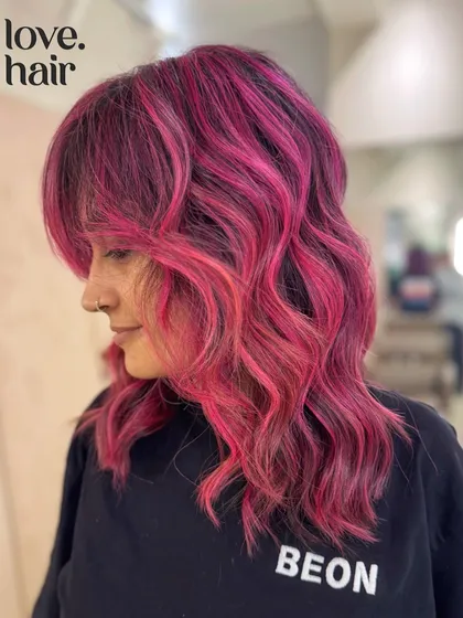 A side view of this pink balayage, showing how the color complements the client's shag haircut and bangs.