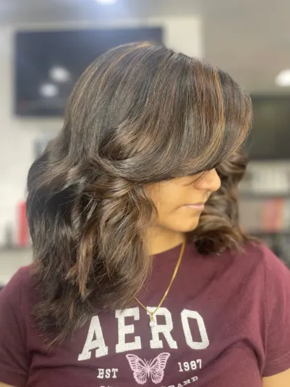 This voluminous, layered style is enhanced with subtle highlights to create depth and texture.