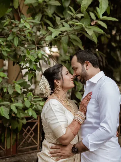A romantic portrait that tells a story. Set against a natural green background, this image captures an intimate moment, highlighting the beautiful details of the bride's attire and the couple's deep connection.