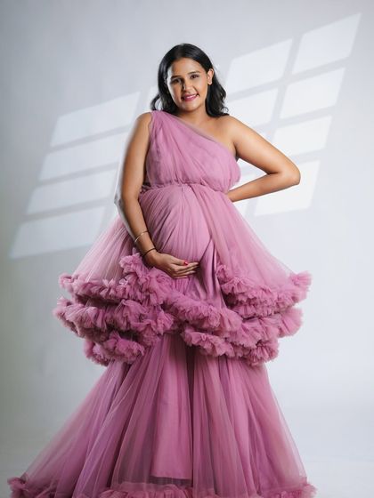 A happy and confident pose from the mom-to-be in our pink ruffled gown. This image captures the joyful spirit of pregnancy.