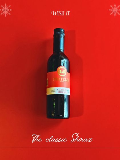A minimalist shot of the classic Shiraz wine included in our Holiday Crate, set against a festive red background.
