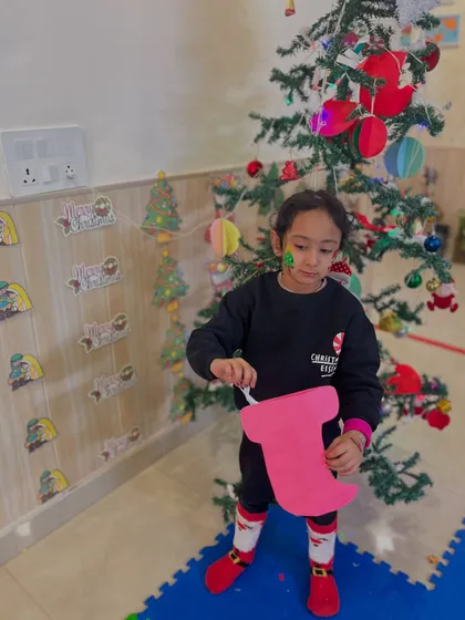 This child hangs her handmade stocking decoration near the tree.