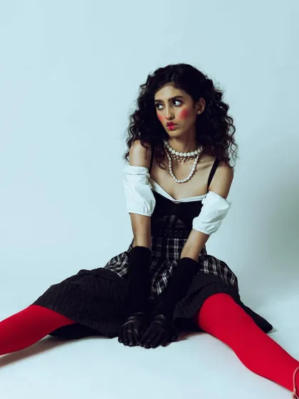 The off-camera gaze in this shot adds to the doll-like, slightly vacant expression. It's a character-driven portrait that tells a story through posing and styling.