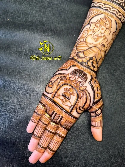This designer mehandi combines a portrait of Lord Ganesha on the arm with a peacock and kalash motif on the palm. It's a beautiful blend of spirituality and tradition.