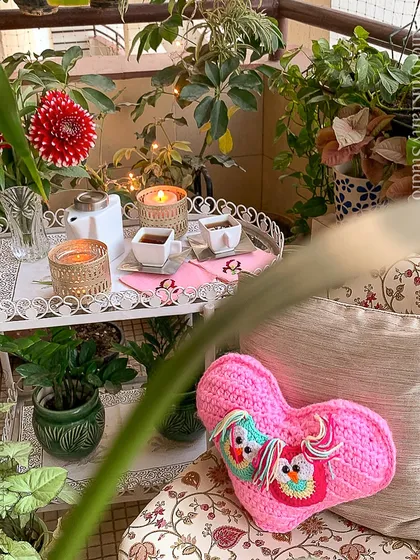 A wider view of the Valentine's cushion in a beautiful balcony garden, surrounded by plants and candlelight. It’s a perfect setting for a cozy, romantic evening.
