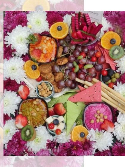 Our Mezze platters are a feast of colours and textures. This overhead shot shows a beautiful arrangement of dips, olives, fruits, and crackers nestled in a bed of fresh flowers.