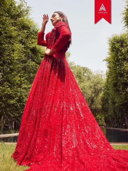 This unforgettable red gown, fully embellished with sequins, is a masterpiece of modern couture. Its dramatic silhouette and fluid train are designed for the bride who is bold, confident, and ready to make a lasting statement.