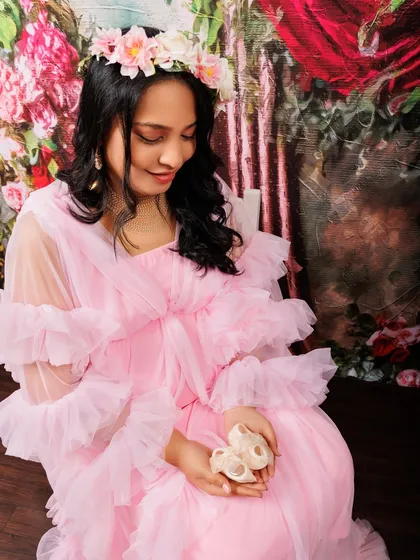 It’s the little details that hold so much meaning. Here, an expecting mother in a soft pink gown holds a tiny pair of baby shoes, a sweet symbol of the little one on the way. I love incorporating personal or symbolic props to make your maternity photos even more special.