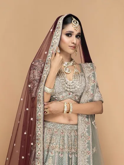 A beautifully tailored bridal lehenga with a sheer maroon dupatta. Our custom service ensures that every component of your outfit, including the draping, is designed for a flawless and elegant appearance.
