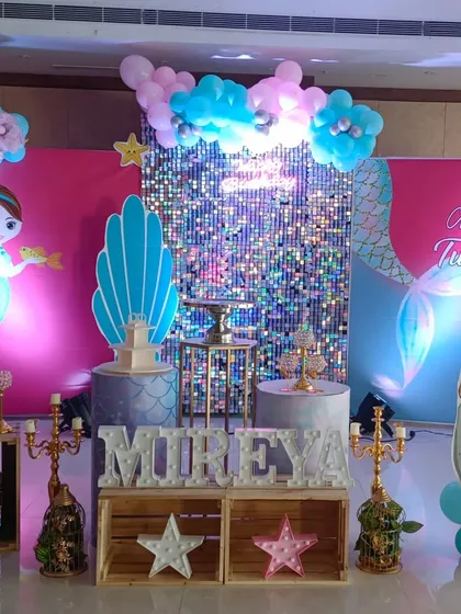 For this third birthday, I created a full mermaid theme. The setup includes a silver shimmer wall for sparkle, character cutouts, a personalized life-size cutout of the birthday girl, and themed pedestals for the cake and desserts.