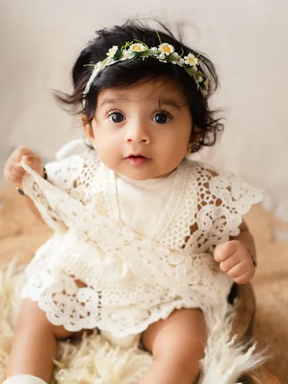 A curious gaze from an 8-month-old baby. The simple, neutral props and background keep the focus entirely on her beautiful expression.