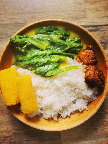 A simple, everyday meal plate with a North-Eastern touch. It includes rice, mustard leaves cooked with dal, fried chicken, and crispy fryums.