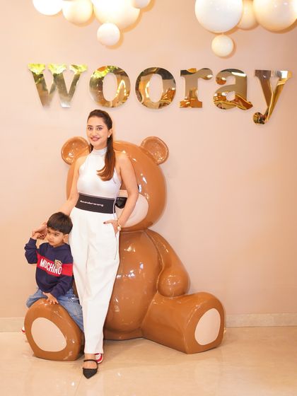 A happy mother posing with our giant teddy bear mascot at her son's superhero-themed third birthday party. Our mascots add an element of fun for everyone.