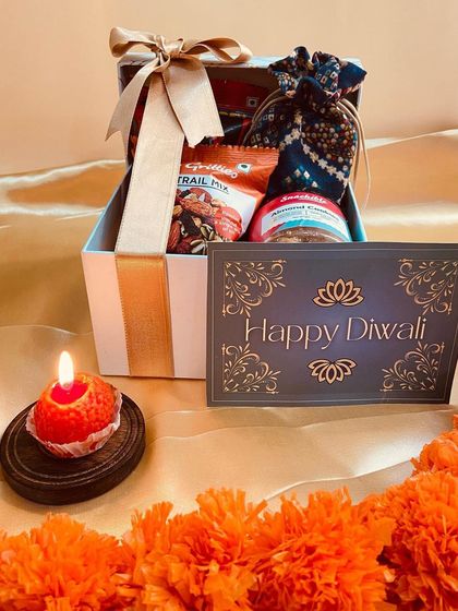 Our striped gift box, beautifully presented with a lit candle and marigold garland, capturing the essence of Diwali.
