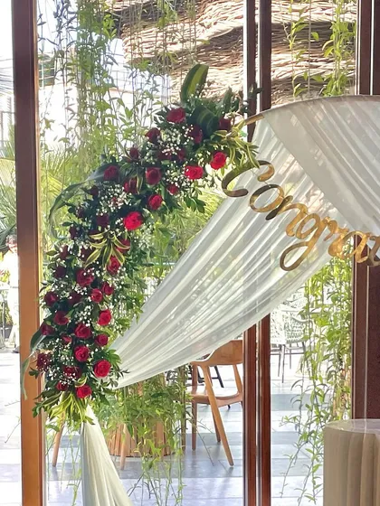 A close-up of the floral arrangement on the circular arch, showcasing the deep red roses and delicate baby's breath.